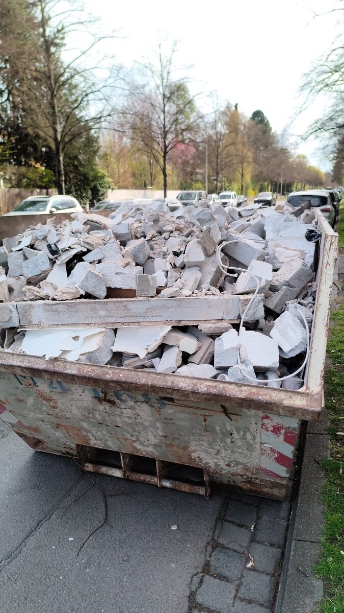 Container voller Bauschutt nach Abriss des alten Badezimmers