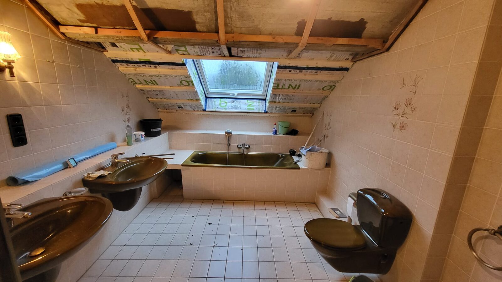 Eingemauerte olivgrüne Wanne unter dem Dachfenster