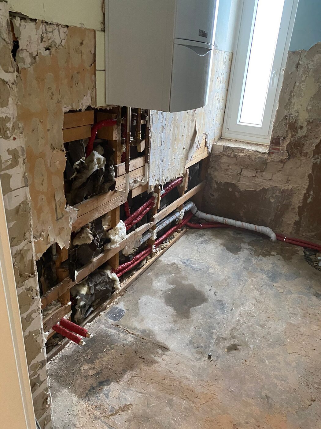 Geöffnete Innenwand mit Fachwerk und neuen roten Wasserleitungen