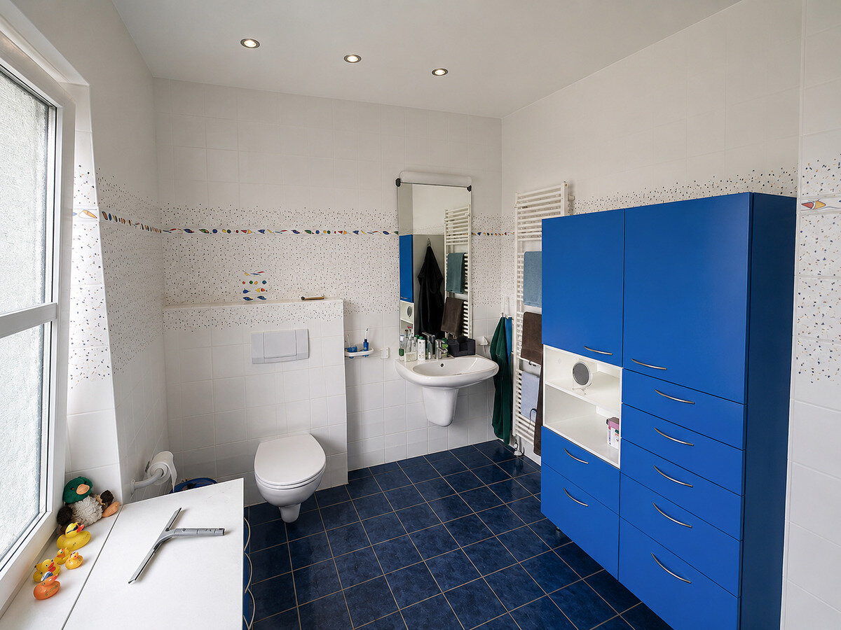 Das Bad vorher: weiß-blaue Wände, freistehendes Waschbecken und alte Leitungen