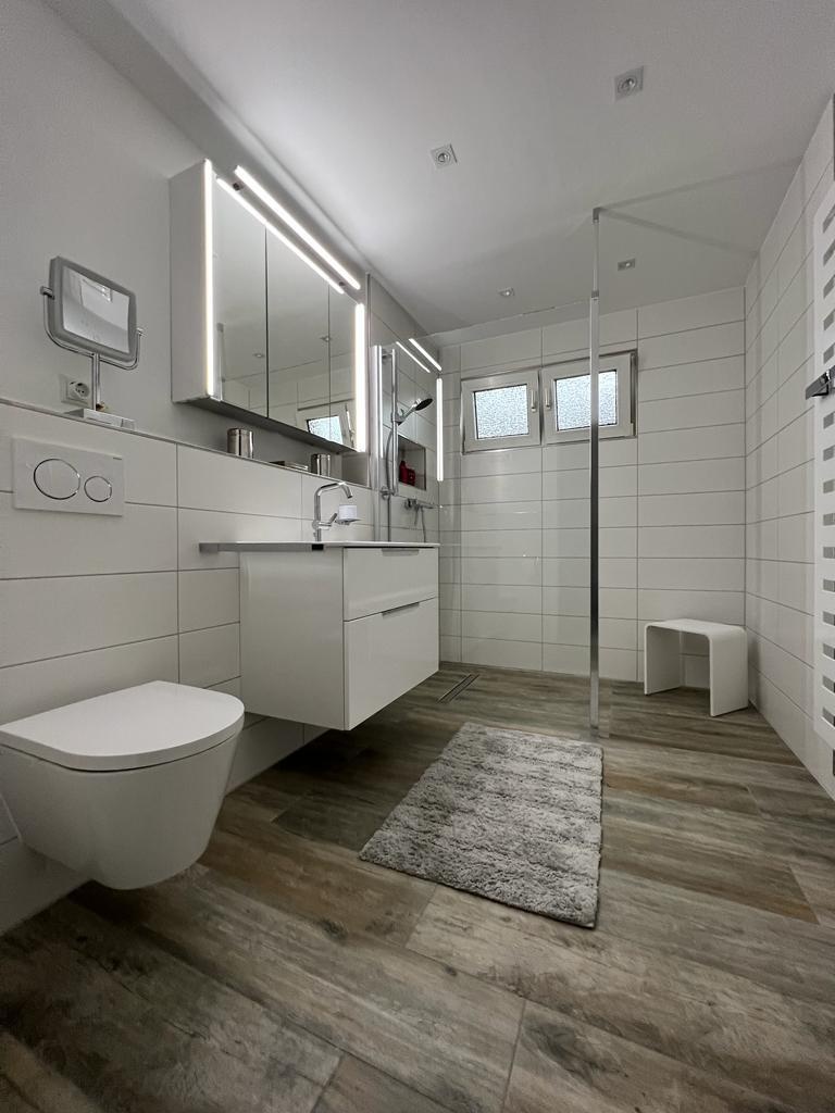 Komfortables Badezimmer mit Wand-WC, Waschtisch und bodengleicher Dusche
