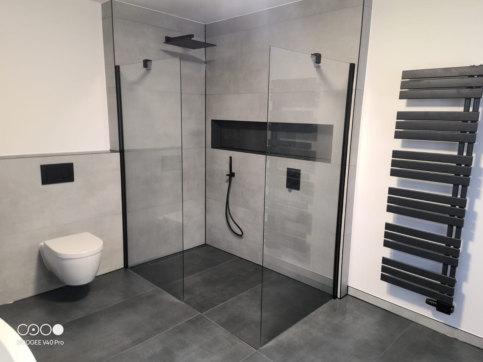 Bodengleiche Walk-in-Dusche mit zwei Glaswänden und schwarzem Design-Heizkörper