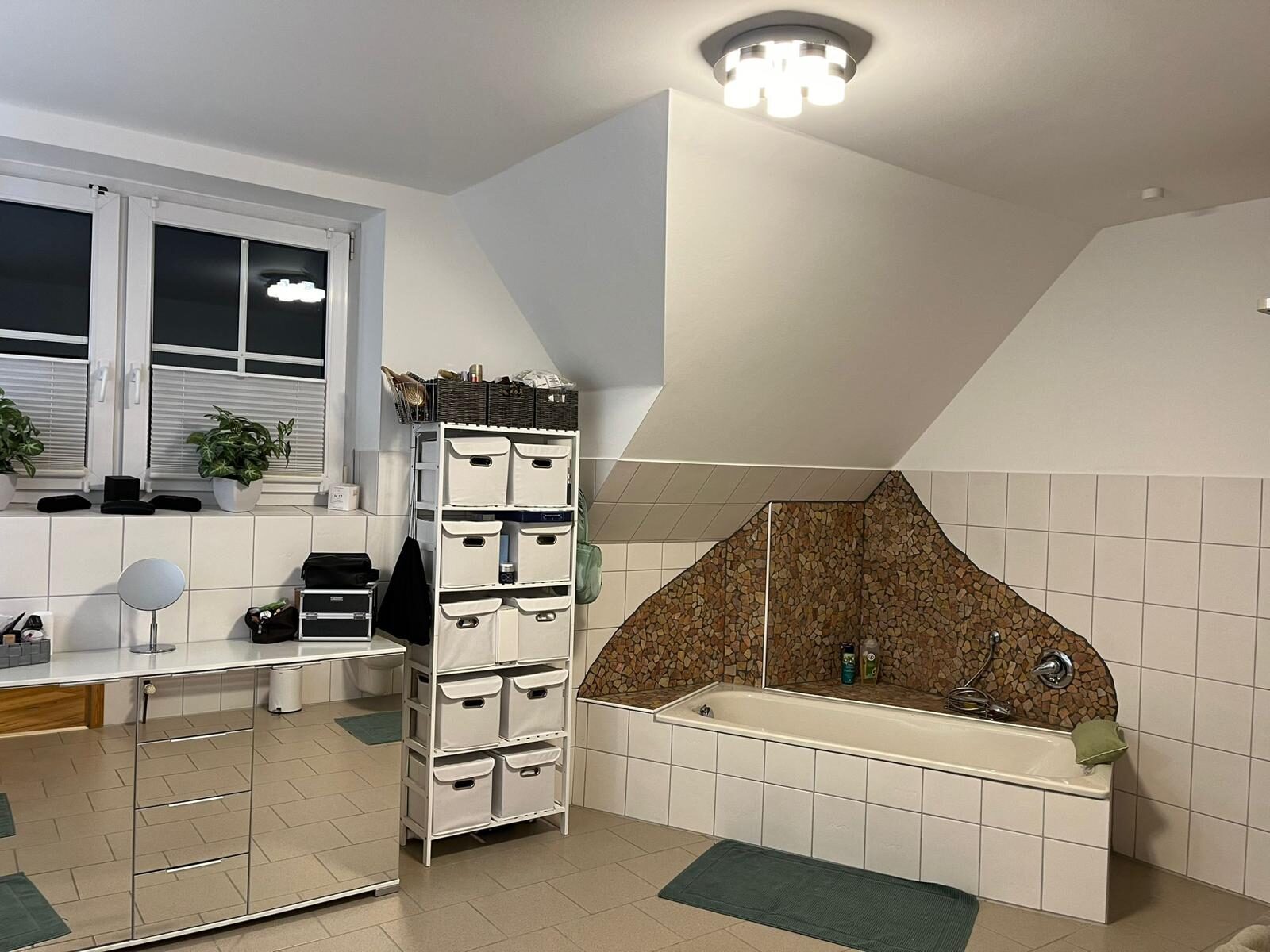 Das Bad vorher: weiße Fliesen, eingemauerte Wanne mit Bruchstein-Mosaik