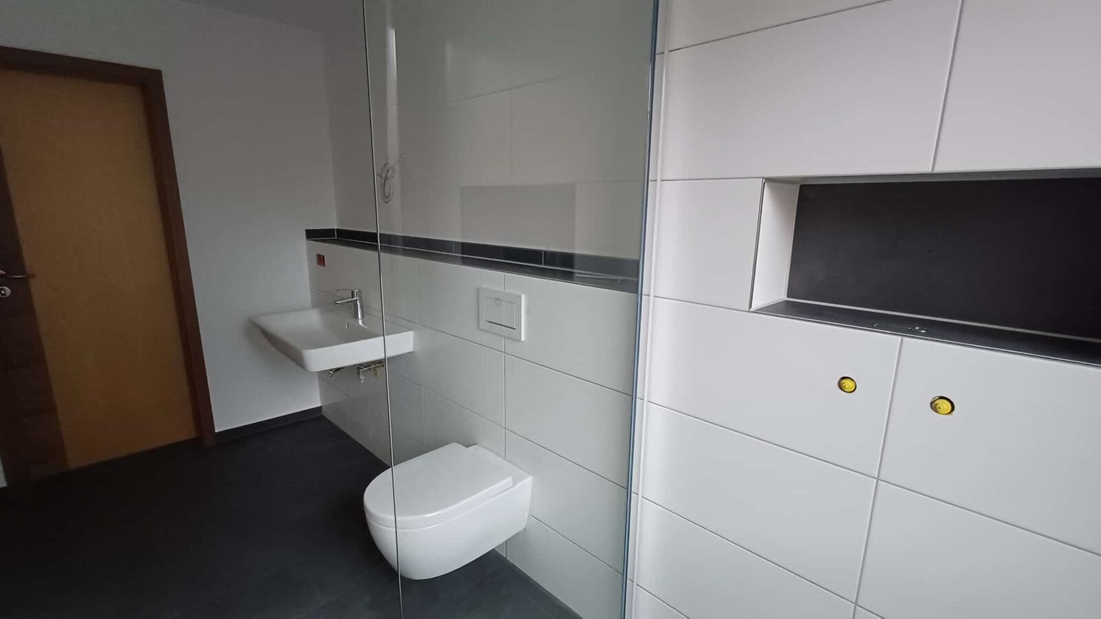 Fertiges Bad mit Wand-WC, Waschtisch und Glaswand der Dusche