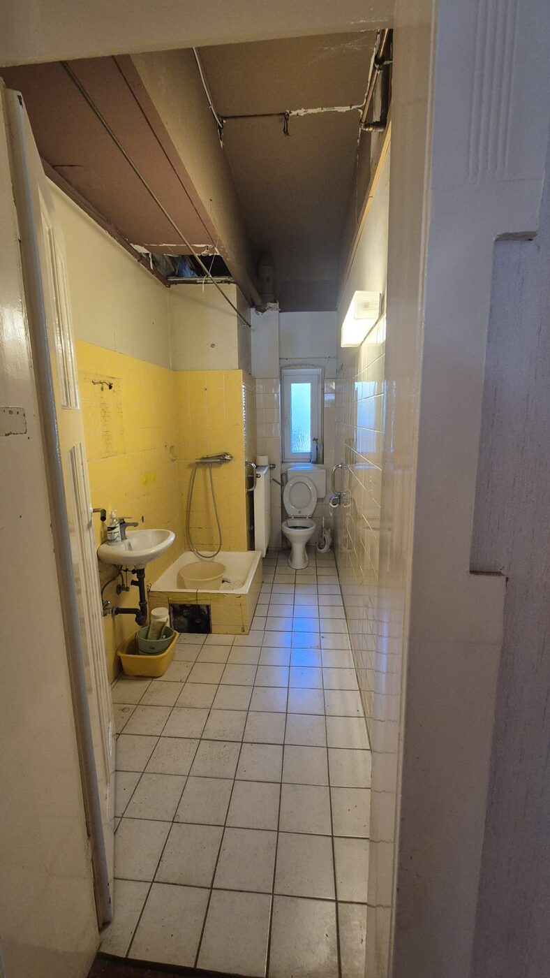 Das Bad vorher: gelbe Wandfliesen, alte Wanne und WC mit Spülkasten