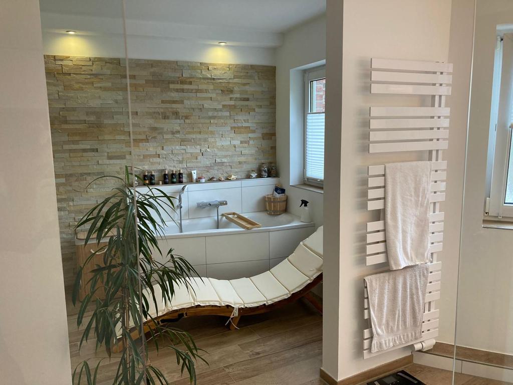 Hochwertig saniertes Wellnessbad mit Badewanne, Natursteinwand und Liege in Hannover