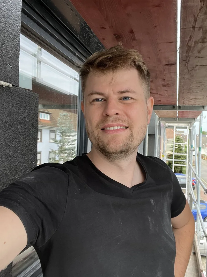 Nils Munzert, Geschäftsführer von Munzert Sanitär, auf einem Gerüst vor einer gedämmten Fassade in Hannover